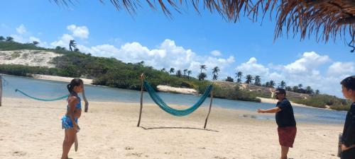 a man and a woman on a beach with a hammock at Casa Boa Venttura Guajiru 3 quartos com ar e piscina in Trairi