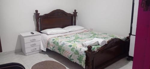 um quarto com uma cama com uma cabeceira em madeira e uma mesa de cabeceira em Vivienda Turística El Paraíso em Génova