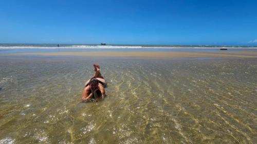 a person laying in the water at the beach at Casa Boa Venttura Guajiru 3 quartos com ar e piscina in Trairi