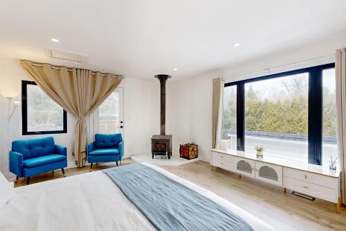 a bedroom with a large bed and two blue chairs at Rolling River Retreat in Midhurst