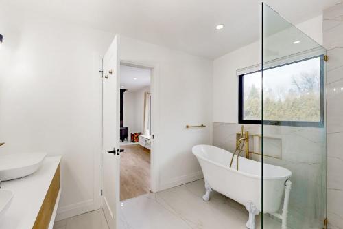 a white bathroom with a tub and a glass door at Rolling River Retreat in Midhurst