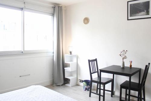 een slaapkamer met een tafel en stoelen en een raam bij Nice studio close to Paris in Montrouge