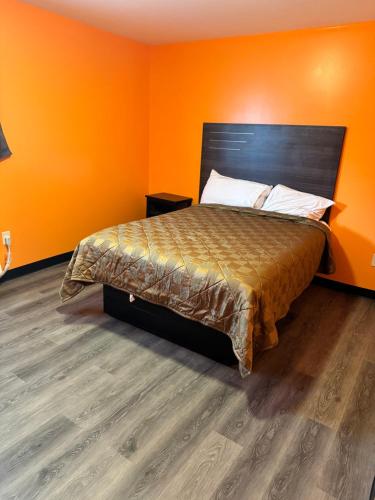 a bedroom with a bed with an orange wall at Budget Inn Decatur Priceville in Decatur