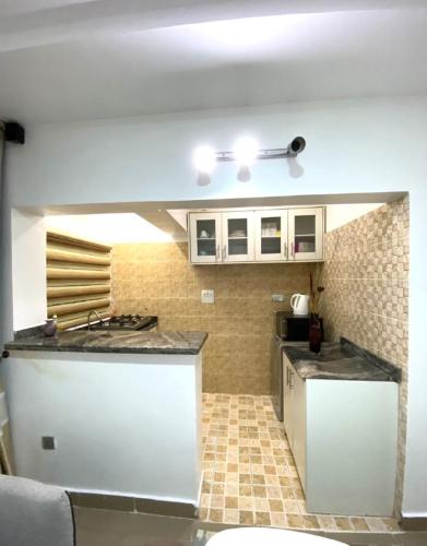 a kitchen with white cabinets and a tile floor at Asokoro Guest House. in Abuja