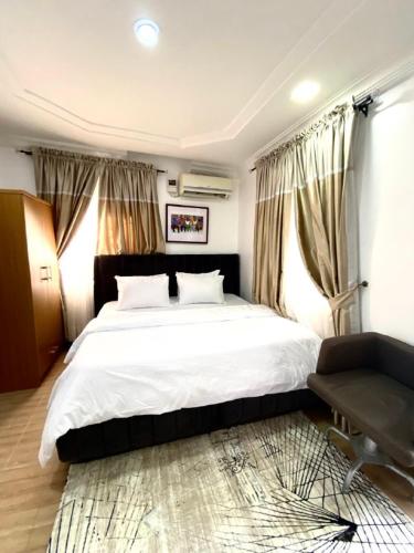 a bedroom with a large white bed and a window at Asokoro Guest House. in Abuja