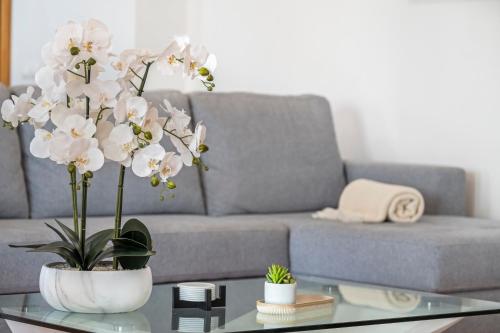 a living room with a couch and a table with white flowers at Sun Hills Panoramic Views in Funchal