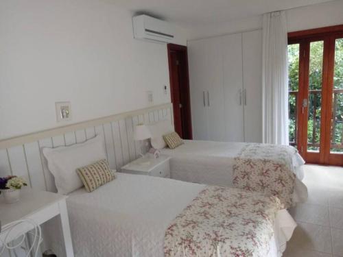 una camera da letto bianca con due letti e una finestra di Casa de Luxo Costa do Sauipe a Mata de Sao Joao