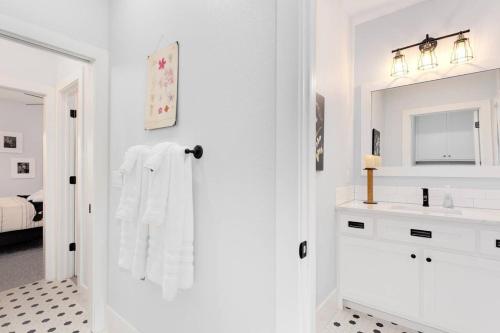 a white bathroom with a sink and a mirror at The Brownstone-1 Block to Downtown Bentonville in Bentonville