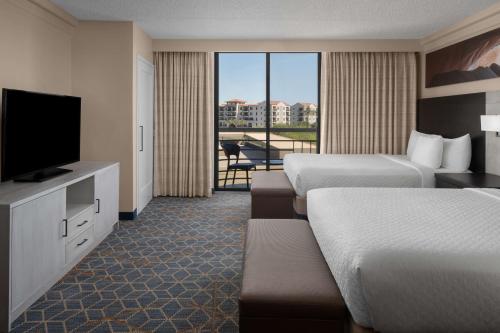 Embassy Suites by Hilton Phoenix Biltmore في فينكس: غرفة فندقية بسريرين وتلفزيون بشاشة مسطحة