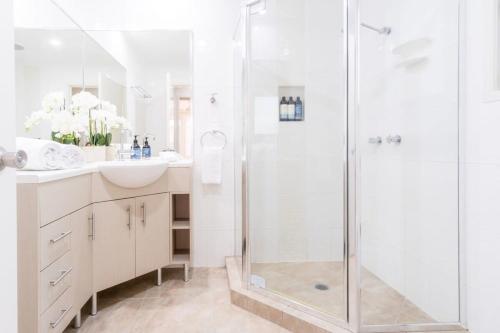 a white bathroom with a shower and a sink at Coolum Family Hideaway - Private Pool & Sauna in Coolum Beach