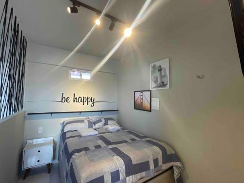 1 dormitorio con 1 cama y un cartel feliz en la pared en kitchenette espetacular na torre en João Pessoa