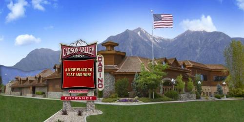 a sign in front of a house with a flag at Carson Valley Motor Lodge and Suites in Minden