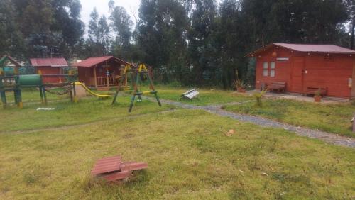 une cour avec une aire de jeux et une maison dans l'établissement Mundo Nuevo Cabañas, à Ráquira