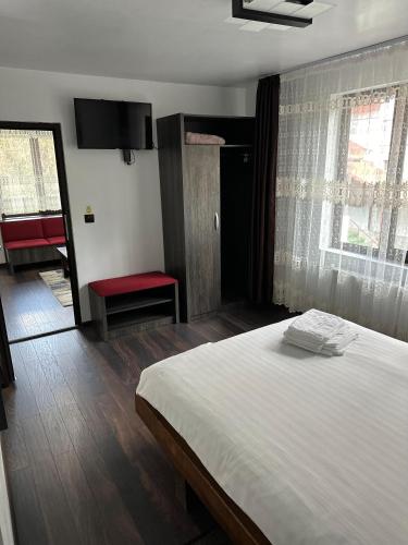 a bedroom with a white bed and a red chair at Vila Agata in Sinaia