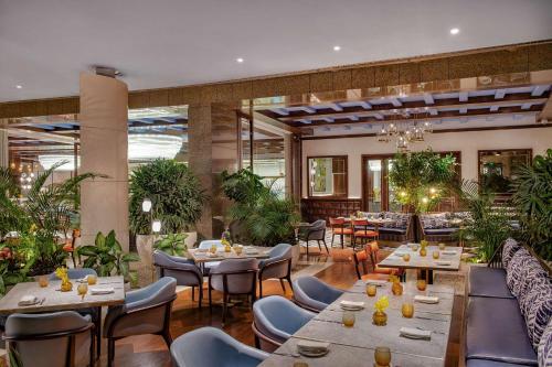 a restaurant with tables and chairs and plants at Waldorf Astoria Cairo Heliopolis in Cairo