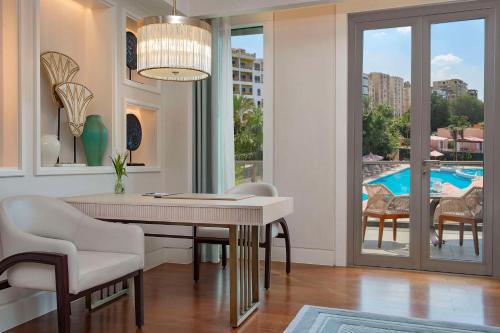 a dining room with a table and chairs and a pool at Waldorf Astoria Cairo Heliopolis in Cairo
