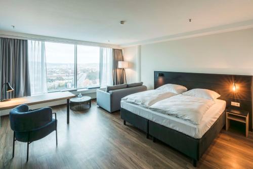 una habitación de hotel con una cama grande y una silla en GHOTEL hotel & living Würzburg en Würzburg