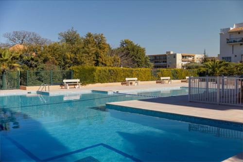 - une piscine d'eau bleue et deux bancs dans l'établissement T2 avec terrasse. Résidence piscine/parking, à Saint-Tropez