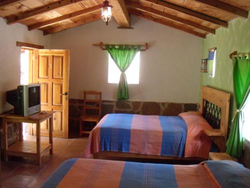 1 dormitorio con 2 camas, TV y ventana en Villa Amacalli, en Tlalpujahua de Rayón