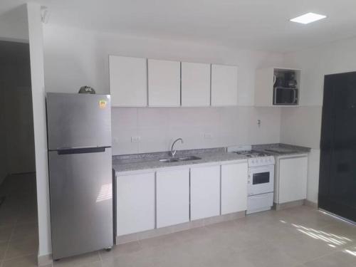 uma cozinha com armários brancos e um frigorífico em Alquiler Casa Guaymallen em Guaymallén