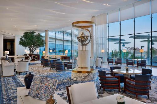 un vestíbulo del hotel con mesas, sillas y ventanas en Waldorf Astoria Lusail, Doha, en Doha