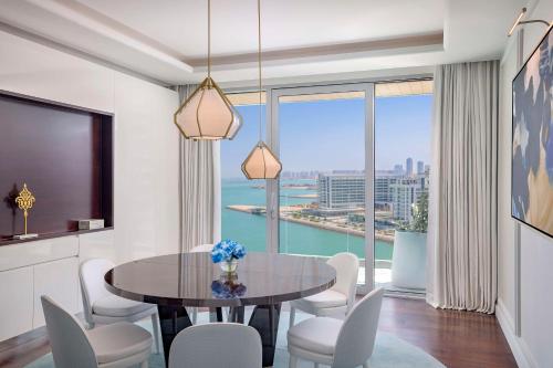 a dining room with a table and chairs and a large window at Waldorf Astoria Doha Lusail in Doha