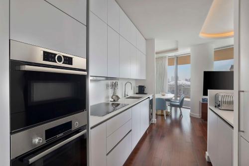 a kitchen with white cabinets and stainless steel appliances at Waldorf Astoria Doha Lusail in Doha