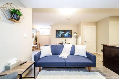 a blue couch in a living room with a table at Bright Modern Suite - Netflix - WiFi - Long Stays in Edmonton