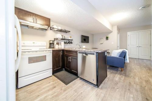 an open kitchen with white appliances and a blue couch at Bright Modern Suite - Netflix - WiFi - Long Stays in Edmonton