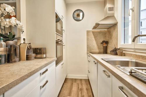 a kitchen with white cabinets and a sink at Trocadéro - Place de Mexico in Paris