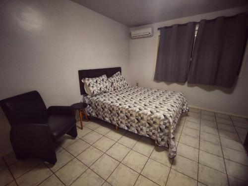 un dormitorio con una cama y una silla en Apartamento Parque Itaimbé - Centro - Garagem, en Santa Maria