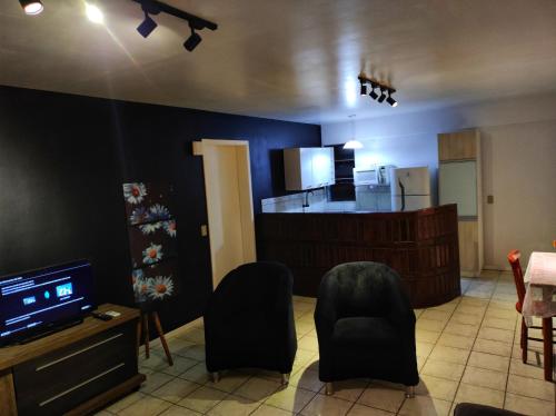 una sala de estar con paredes y sillas negras y una cocina. en Apartamento Parque Itaimbé - Centro - Garagem, en Santa Maria