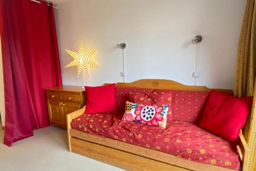 - un canapé rouge avec des oreillers rouges dans l'établissement Nice ski nest in Dévoluy, à Saint-Étienne-en-Dévoluy