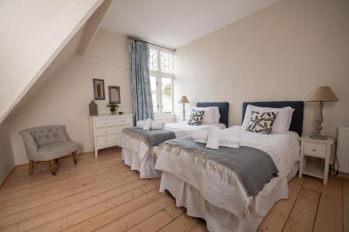 a bedroom with two beds and a chair and a window at Fairhaven in Dartmouth