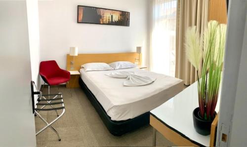 1 dormitorio con 1 cama y 1 silla roja en Corso, en Eforie Sud
