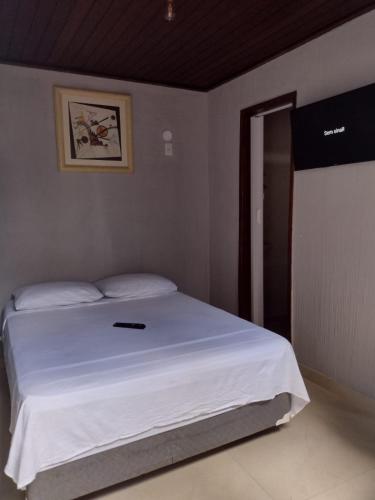 - une chambre dotée d'un lit blanc avec une photo sur le mur dans l'établissement Suíte Verano 1,2,3 e 4, à Niterói