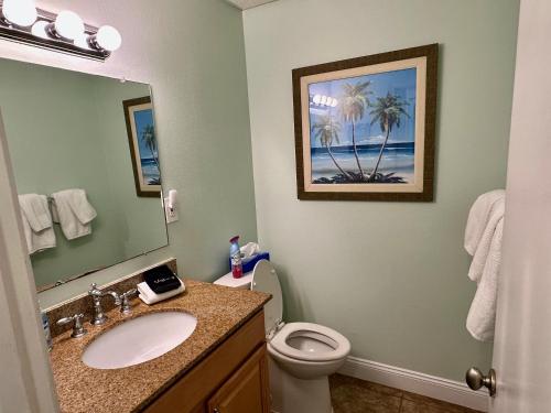 a bathroom with a sink and a toilet and a mirror at Your Beach Therapy Awaits at Sans Souci in Pensacola Beach
