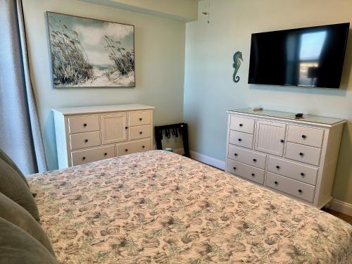 a bedroom with a bed and a dresser and a flat screen tv at Your Beach Therapy Awaits at Sans Souci in Pensacola Beach