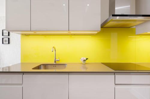 een keuken met een wastafel en een gele muur bij Spitafields 2 Bed Shoreditch Apartment in Londen