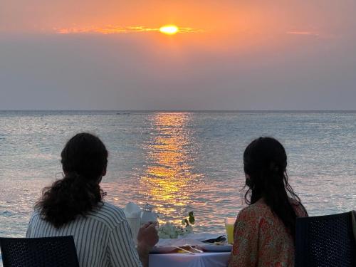 two people sitting at a table watching the sunset at Boli Villa Thoddoo in Thoddoo
