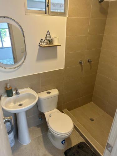 ein Badezimmer mit einem WC, einem Waschbecken und einem Spiegel in der Unterkunft Departamento de Estreno in Candelaria