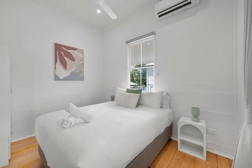 a white bedroom with a white bed and a window at Charming 3-Bedroom Retreat in Townsville