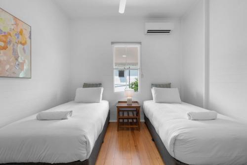 two twin beds in a room with a window at Charming 3-Bedroom Retreat in Townsville