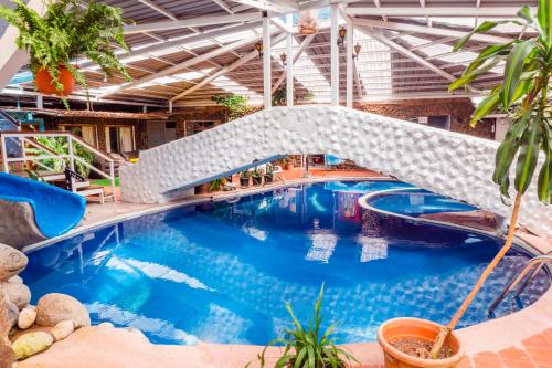 a swimming pool with a bridge in a building at Spa Hosteria Miramelindo in Baños