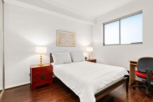 Schlafzimmer mit einem Bett, einem Schreibtisch und einem Fenster in der Unterkunft Spacious 1-Bed with Pool & Gym 5 Minutes from CBD in Sydney