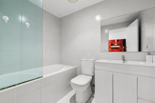a white bathroom with a toilet and a sink at Spacious 1-Bed with Pool & Gym 5 Minutes from CBD in Sydney