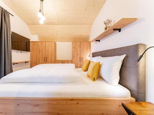 a bedroom with a white bed with a wooden headboard at Falken Suites TOP 8 in Kaprun
