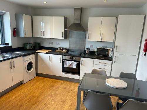 a kitchen with white cabinets and a table with chairs at Long Stay - Free Parking - Contractors - Train Station - Students in Colchester