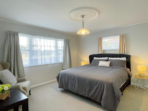 a bedroom with a bed and a chair and windows at Home in central Auckland in Auckland