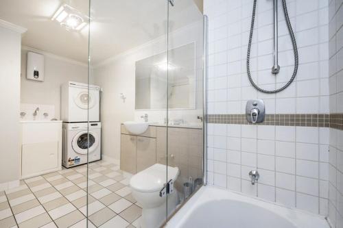 y baño con aseo y lavadora. en Convenient 2-Bed Apartment in the Heart of Perth en Perth